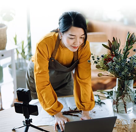 Woman leaning over table working on laptop